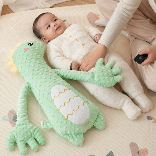 Parent supervising an awake baby while the MEACAOFG green dinosaur toy demonstrates gentle rhythmic patting
