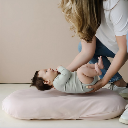 Baby lounging safely on a soft pink baby lounger cushion