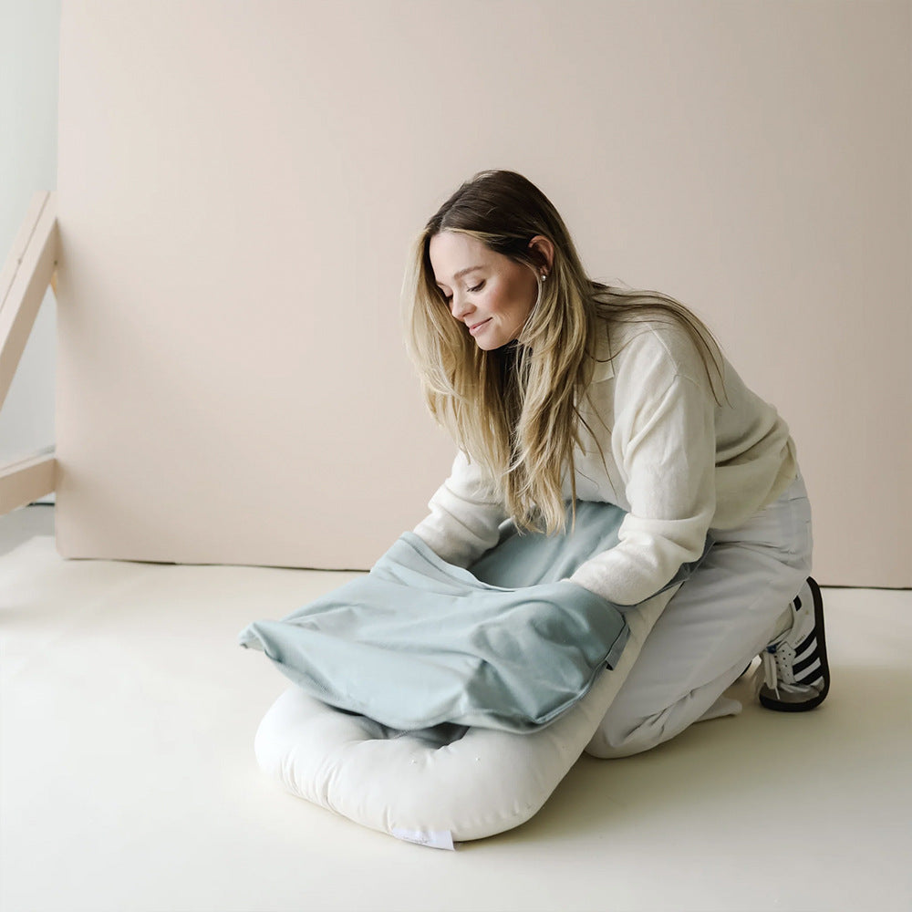 Mother fitting cover on a soft baby lounger cushion