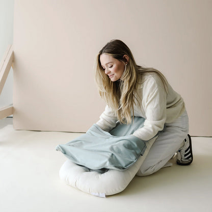 Mother fitting cover on a soft baby lounger cushion
