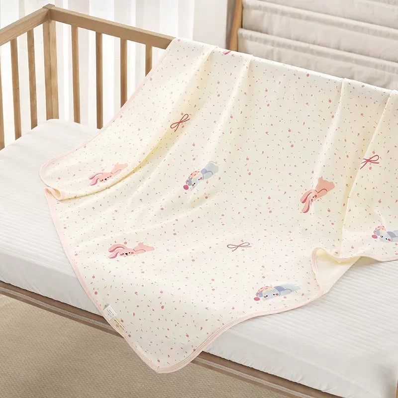 100% organic knit cotton baby swaddle blanket with cute cartoon pattern draped over a wooden newborn crib