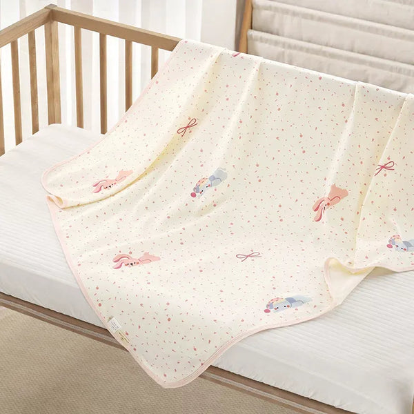 100% organic knit cotton baby swaddle blanket with cute cartoon pattern draped over a wooden newborn crib